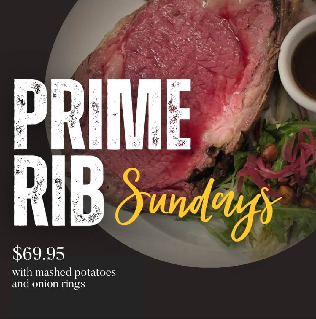 Plate with a slice of prime rib, side salad with onion rings, and a cup of dark au jus sauce, advertising Prime Rib Sundays for $69.95 with mashed potatoes and onion rings.